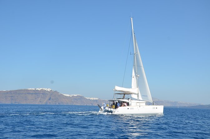 Santorini Caldera Gold Day Cruise with BBQ on board and Open Bar - Akrotiri lighthouse and the Black Mountain stretches that feel cinematic