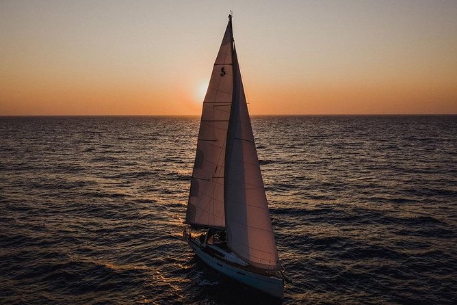 Santorini Caldera Private Sailing Boat Cruise - Akrotiri lighthouse views from the water, plus the dark-rock scenery