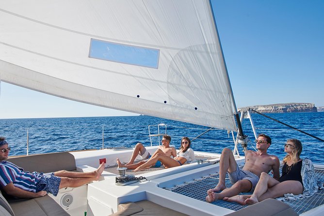 Santorini Gold Catamaran Cruise with BBQ, Drinks and Hotel Pickup - White Beach sailing: limestone glow and quick photo time